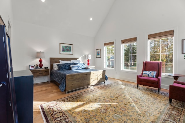 bedroom featuring high vaulted ceiling and light hardwood / wood-style floors