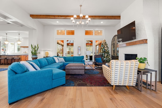 living room with plenty of natural light, beam ceiling, light hardwood / wood-style floors, and french doors