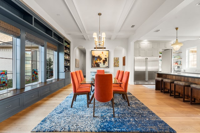 dining room featuring beam ceiling, coffered ceiling, an inviting chandelier, light hardwood / wood-style flooring, and built in features