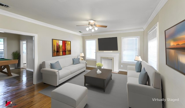 living room featuring visible vents, baseboards, ornamental molding, a fireplace, and wood finished floors