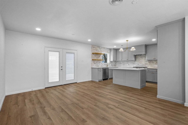 kitchen featuring gray cabinetry, hanging light fixtures, a center island, tasteful backsplash, and stainless steel dishwasher