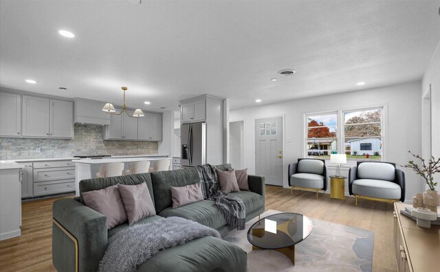 kitchen with a center island, light wood-type flooring, gray cabinets, pendant lighting, and stainless steel appliances