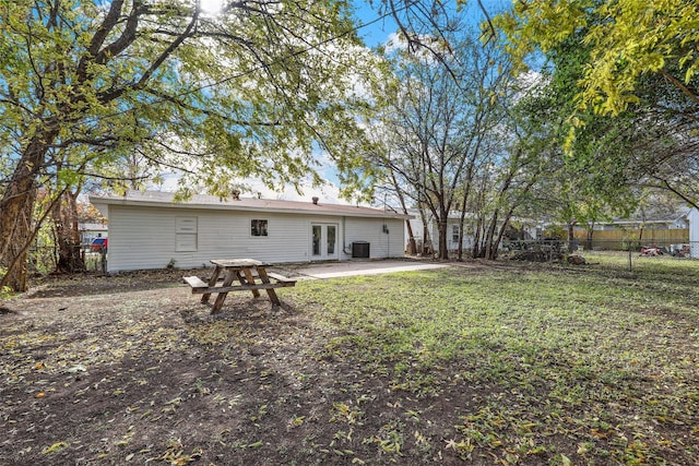 rear view of property with cooling unit, a patio, a lawn, and french doors