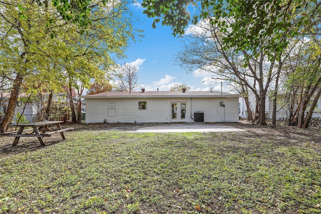 rear view of house featuring cooling unit, french doors, a patio, and a lawn