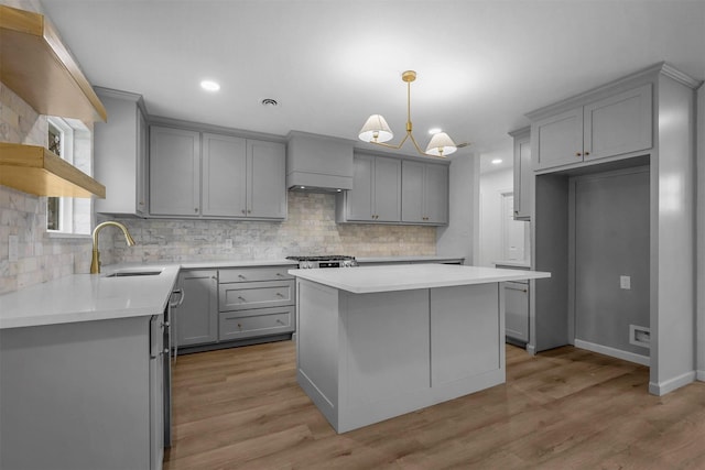 kitchen with sink, gray cabinetry, backsplash, a center island, and light hardwood / wood-style floors