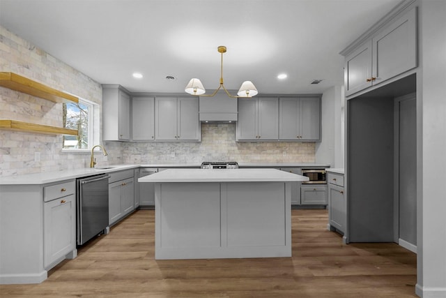 kitchen featuring a kitchen island, pendant lighting, gray cabinetry, light hardwood / wood-style floors, and stainless steel appliances