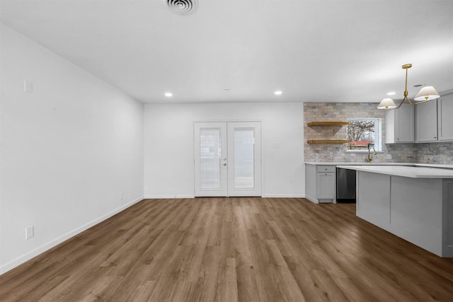 kitchen with gray cabinets, decorative light fixtures, backsplash, dark hardwood / wood-style flooring, and stainless steel dishwasher