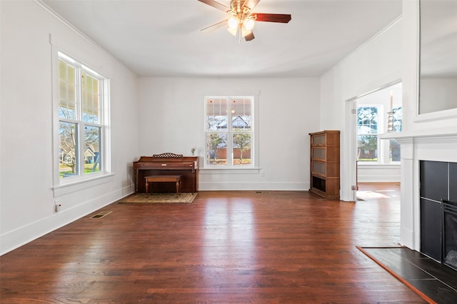 unfurnished living room featuring ceiling fan, crown molding, and dark wood-type flooring