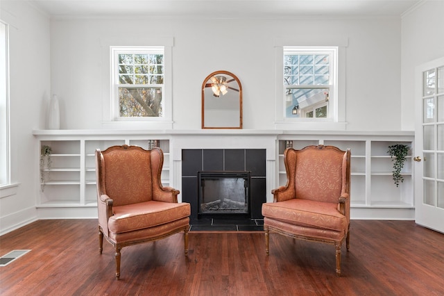 living area with a tile fireplace, hardwood / wood-style floors, and ornamental molding