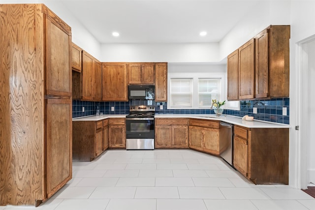 kitchen featuring decorative backsplash, appliances with stainless steel finishes, and light tile patterned flooring