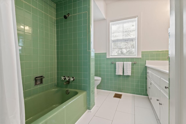 full bathroom with vanity, tile walls, tile patterned flooring, toilet, and tiled shower / bath