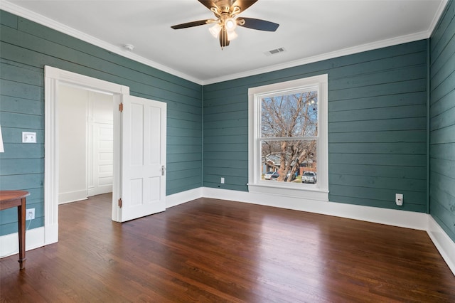 spare room with ceiling fan, dark hardwood / wood-style floors, crown molding, and wooden walls