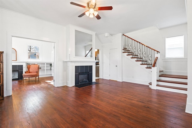 unfurnished living room featuring ceiling fan, dark hardwood / wood-style flooring, a fireplace, and crown molding