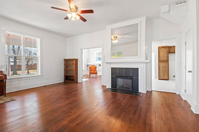 unfurnished living room featuring dark hardwood / wood-style floors, ceiling fan, and a tiled fireplace