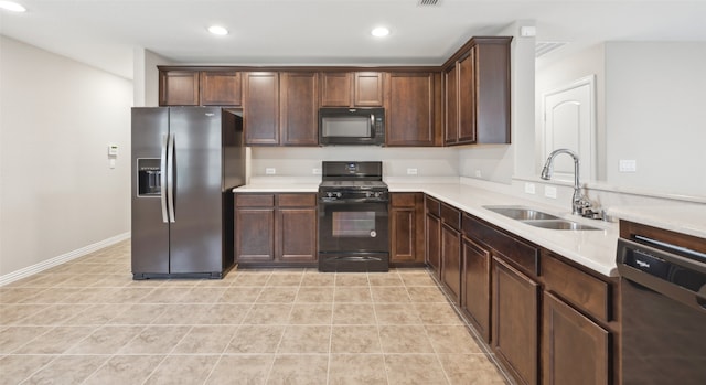 kitchen featuring dark brown cabinets, sink, light tile patterned floors, and black appliances