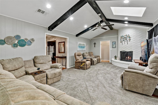 living room featuring ceiling fan, carpet floors, wooden walls, a fireplace, and vaulted ceiling with skylight