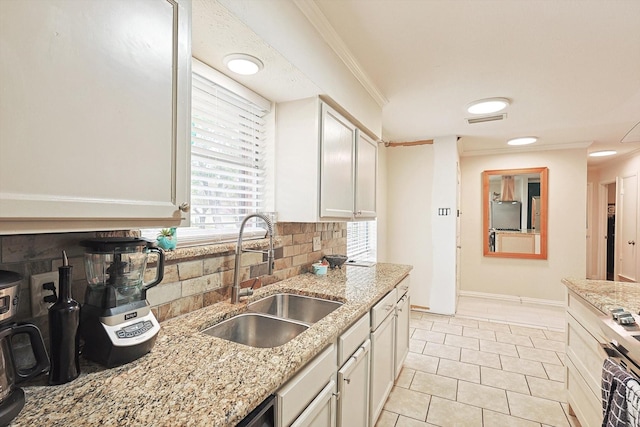 kitchen with light stone countertops, backsplash, ornamental molding, stainless steel range, and sink