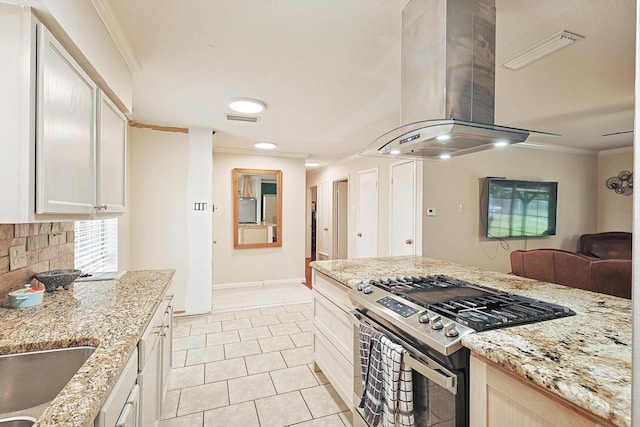 kitchen featuring light tile patterned floors, gas stove, island range hood, and crown molding