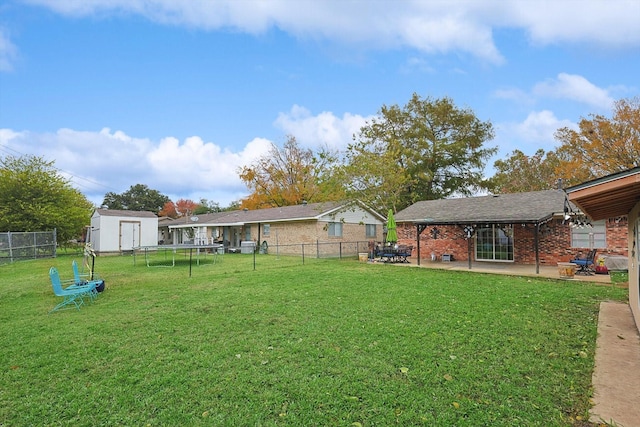 view of yard featuring a trampoline, a shed, and a patio area