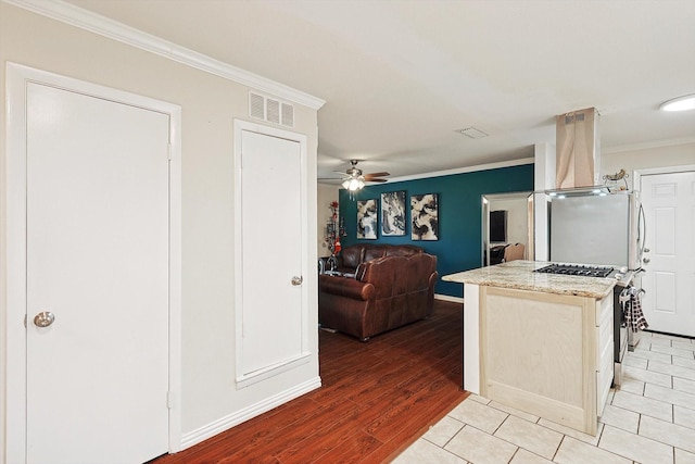 kitchen featuring stainless steel fridge, light wood-type flooring, ornamental molding, gas range, and extractor fan