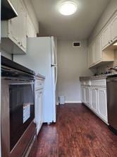 kitchen featuring range, ventilation hood, white refrigerator, stainless steel dishwasher, and white cabinetry