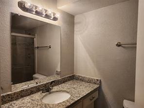 bathroom featuring walk in shower, vanity, and toilet