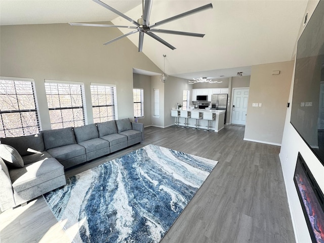 living room featuring a large fireplace, dark wood-type flooring, high vaulted ceiling, and ceiling fan