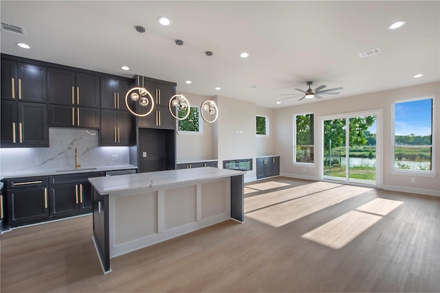 kitchen with ceiling fan, a center island, light hardwood / wood-style floors, and sink