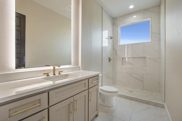 bathroom featuring tiled shower, vanity, and toilet