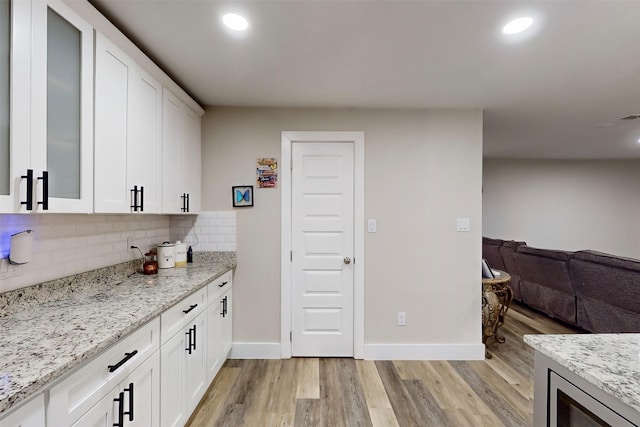 bar with white cabinetry, light stone countertops, and light wood-type flooring