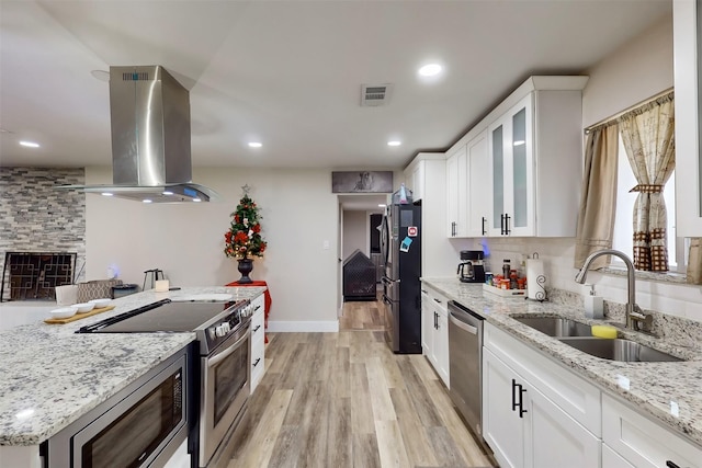 kitchen with white cabinets, sink, appliances with stainless steel finishes, island range hood, and light stone counters