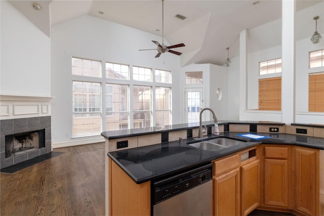 kitchen featuring dishwasher, dark wood-type flooring, high vaulted ceiling, sink, and a tiled fireplace