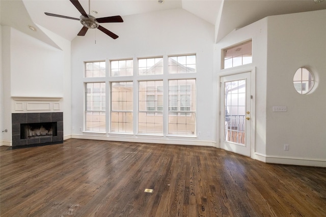 unfurnished living room featuring a fireplace, high vaulted ceiling, ceiling fan, and dark wood-type flooring