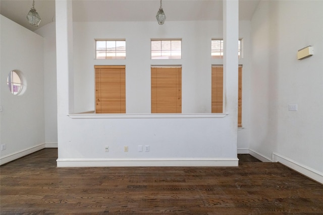 spare room with dark hardwood / wood-style flooring and a high ceiling