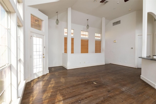 empty room with dark hardwood / wood-style floors, ceiling fan, plenty of natural light, and high vaulted ceiling