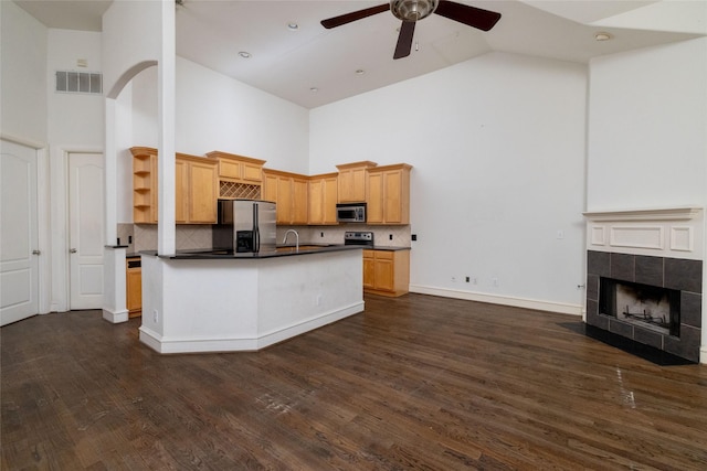 kitchen featuring appliances with stainless steel finishes, light brown cabinetry, ceiling fan, high vaulted ceiling, and dark hardwood / wood-style floors