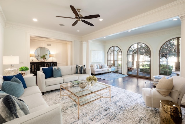 living room featuring ceiling fan, wood-type flooring, ornamental molding, and decorative columns