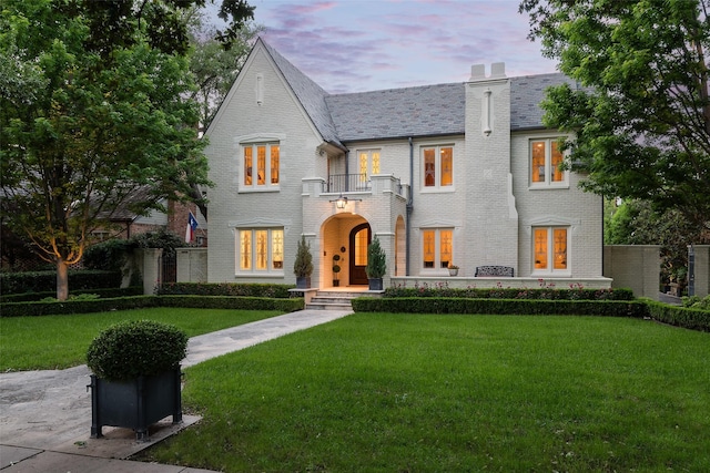 view of front of house featuring a lawn and a balcony