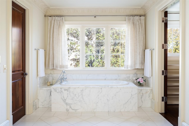 bathroom featuring a relaxing tiled tub and a healthy amount of sunlight