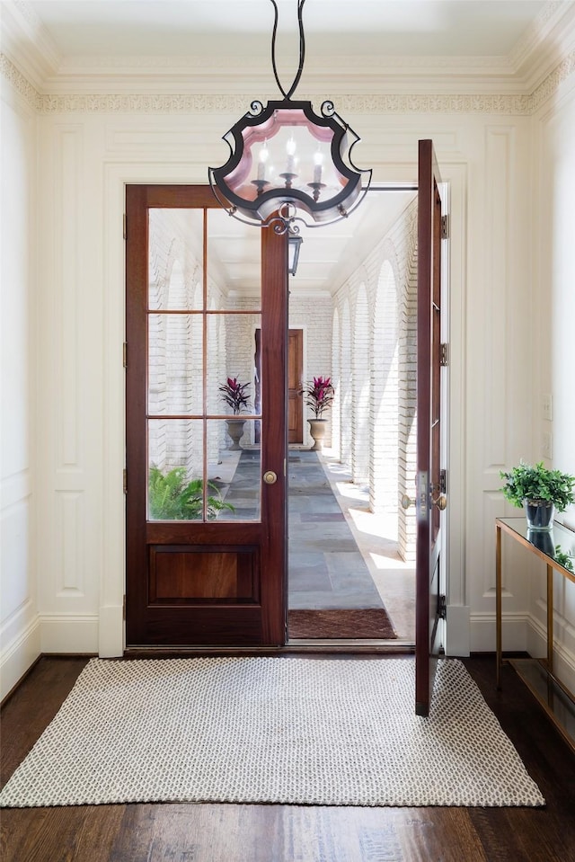 entrance foyer with a chandelier, dark wood-type flooring, crown molding, and a healthy amount of sunlight