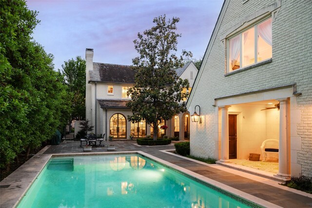 pool at dusk featuring a patio area