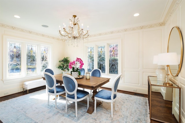 dining area with dark hardwood / wood-style floors, ornamental molding, and a notable chandelier