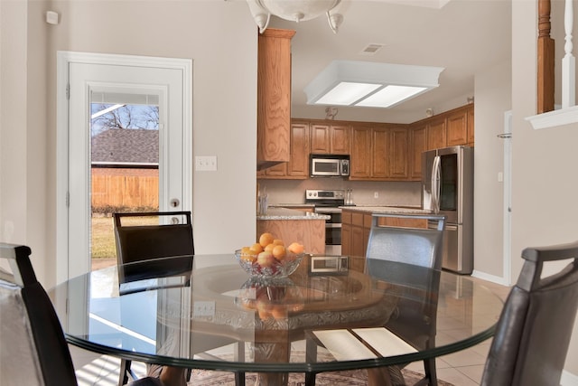 kitchen featuring stainless steel appliances, light tile patterned flooring, light stone counters, and decorative backsplash