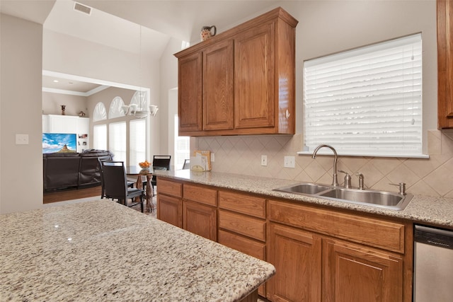 kitchen with dishwasher, sink, backsplash, ornamental molding, and light stone countertops