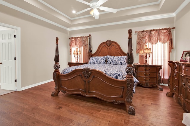 bedroom with crown molding, a tray ceiling, and dark wood-type flooring