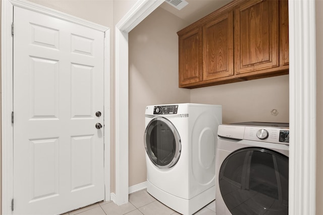 washroom with washer and dryer, cabinets, and light tile patterned floors