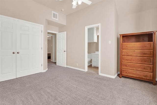 unfurnished bedroom featuring light carpet, connected bathroom, a closet, and ceiling fan