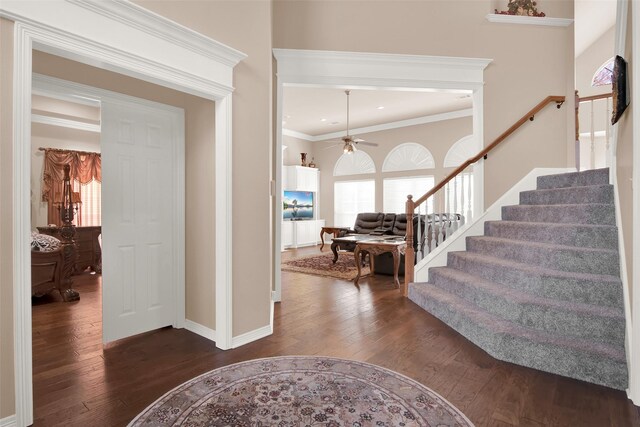 foyer entrance with ceiling fan, ornamental molding, and dark wood-type flooring