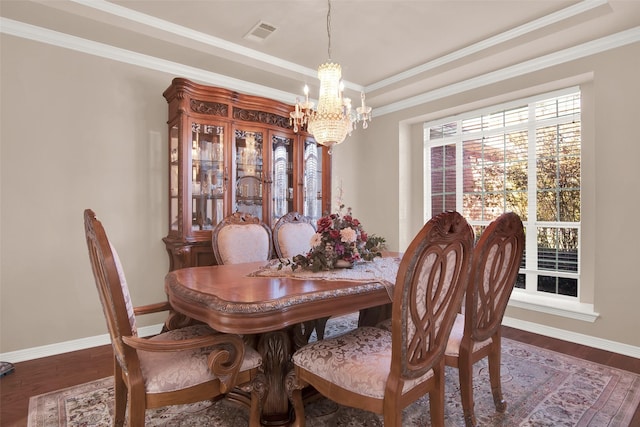 dining space featuring a chandelier, ornamental molding, a raised ceiling, and dark wood-type flooring