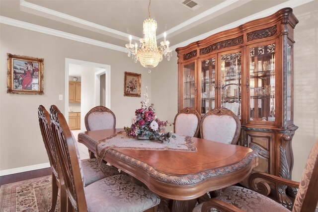 dining area featuring a tray ceiling, crown molding, wood-type flooring, and a notable chandelier